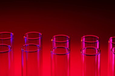 Laboratuvarda kırmızı arka plandaki test tüpleri. Bilim araştırması. Laboratuvar camları yakın çekim. Şeffaf konteynır. Tıp ve güzellik konsepti.