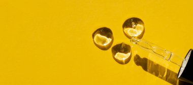 Kapağı yakın çekim damlaları ve serum damlalarıyla açın. Sarı arka plan, gün ışığı ve jel dokusunun görünüşü. Cilt bakım ürünleri, doğal kozmetik ürünleri. Yüz ve vücut bakımı için güzellik konsepti