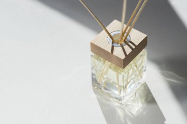 Beyaz arka planda şeffaf aroma yayıcı şişesi. Ev yapımı sunum için parfüm. Moda konsepti. Sarı sıvı ve ahşap kaplama