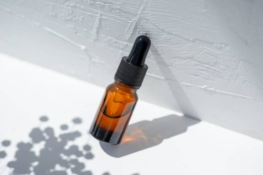 Damla pipetli bir şişe serum ya da gerekli yağ. Beyaz arka plan, gün ışığı ve güzel köşegen gölgeler. Cilt bakım ürünleri, doğal kozmetik ürünleri. Yüz ve vücut bakımı için güzellik konsepti