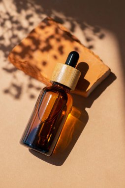 Siyah kapaklı ve çiçekli kehribar cam damlası. Ürün sunumu için kırmızı beton podyumda bir şişe. Cilt bakım ürünleri ve kır çiçekleri. Güzellik konsepti