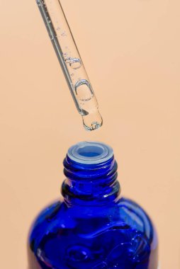 Serumlu damlacık pipeti mi yoksa mavi şişeli yağ mı? Cilt ürünleri, bej arka planda doğal kozmetik ürünleri. Yüz ve vücut bakımı için güzellik konsepti.
