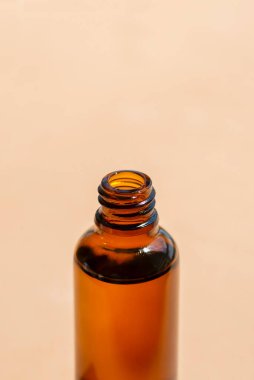 Kehribar şişesini serumsuz ya da hafif odaklı gerekli yağlı aç. Bej arka plan, gün ışığı ve güzel gölgeler. Yüz ve vücut bakımı için güzellik konsepti