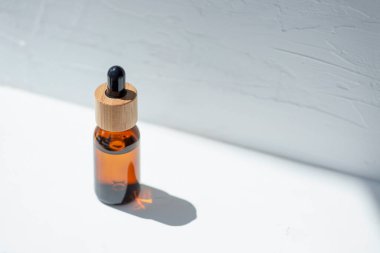 Şişede damla pipeti ve serum ya da gerekli yağ var. Beyaz arka plan, gün ışığı ve güzel gölgeler. Cilt bakım ürünleri, doğal kozmetik ürünleri. Yüz ve vücut bakımı için güzellik konsepti