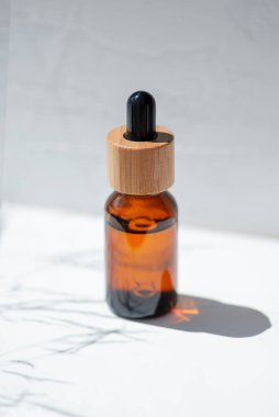 Şişede damla pipeti ve serum ya da gerekli yağ var. Beyaz arka plan, gün ışığı ve güzel gölgeler. Cilt bakım ürünleri, doğal kozmetik ürünleri. Yüz ve vücut bakımı için güzellik konsepti