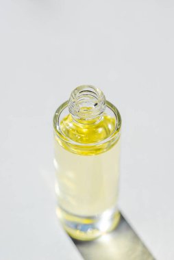 Şeffaf şişeyi serumla kapaksız açın ya da yumuşak odaklı gerekli yağla. Beyaz arka plan, gün ışığı ve güzel gölgeler. Yüz ve vücut bakımı için güzellik konsepti