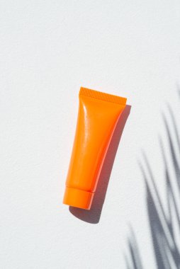 Beyaz arka planda krem ya da losyon için plastik turuncu şişe. Güzel palmiye gölgeli cilt kozmetiği. Yüz bakımı için güzellik konsepti