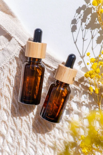 Kehribar şişe damlası pipeti, serum ya da gerekli yağ ve bez torbası, güzel bir tarla çimeni. Beyaz arka plan, gün ışığı ve gölgeler. Yüz bakımı için güzellik konsepti