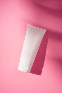 Krem veya losyon için plastik beyaz tüp. Cilt bakımı ya da güzel gölgeli pembe arka planda güneş kremi. Yüz bakımı için güzellik konsepti