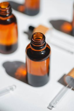 Kehribar şişesini serum ya da gerekli yağla açın. Bambu şapkalı borular. Beyaz arka plan, gün ışığı ve güzel gölgeler. Yüz ve vücut bakımı için güzellik konsepti