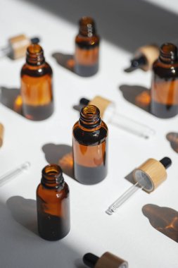 Kehribar şişesini serum ya da gerekli yağla açın. Bambu şapkalı borular. Beyaz arka plan, gün ışığı ve güzel gölgeler. Yüz ve vücut bakımı için güzellik konsepti