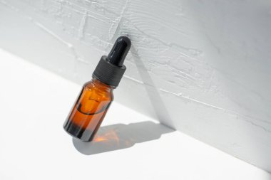 Şişede damla pipeti ve serum ya da gerekli yağ var. Beyaz arka plan, gün ışığı ve güzel gölgeler. Cilt bakım ürünleri, doğal kozmetik ürünleri. Yüz ve vücut bakımı için güzellik konsepti