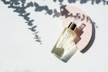 Damlatan pipetli şeffaf bir şişe serum ya da okaliptüs gölgeli pembe beton podyumda gerekli yağ. Gündüz vakti beyaz arka plan. Yüz ve vücut bakımı için güzellik konsepti