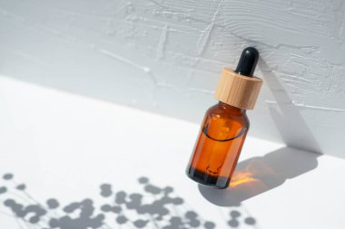 Şişede damla pipeti ve serum ya da gerekli yağ var. Beyaz arka plan, gün ışığı ve güzel gölgeler. Cilt bakım ürünleri, doğal kozmetik ürünleri. Yüz ve vücut bakımı için güzellik konsepti