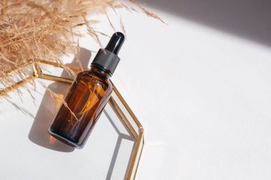 Kehribar cam şişe damlatıcısı pipeti, serum ya da ürün sunumu için cam tabakta gerekli yağ. Cilt makyajı ve kır çiçekleri. Yüz bakımı için güzellik konsepti