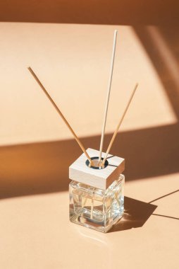 Bej arka planda şeffaf aroma yayıcı şişesi. Ev yapımı sunum için parfüm. Doğal renklerde trend kavramı