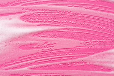 Pembe arka planda köpük örneği. Köpüklü sabunlu sıvı doku. Doğal güneş ve gölgeler. Üst görünümde cilt bakım temizleme kozmetiği.