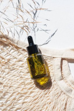 Yeşil şişe damlatıcısı pipeti, serum ya da gerekli yağ ve bez torbası, güzel çim tarlası. Beyaz arka plan, gün ışığı ve gölgeler. Yüz bakımı için güzellik konsepti