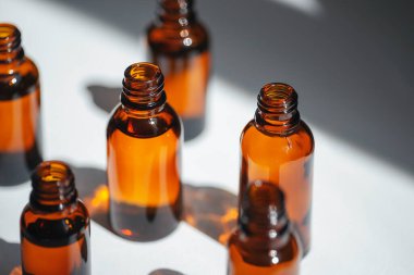 Kehribar şişesini serum ya da gerekli yağla açın. Beyaz arka plan, gün ışığı ve güzel gölgeler. Yüz ve vücut bakımı için güzellik konsepti