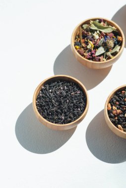 Different types of green, black and herbal tea in a wooden bowl. Variety of dry leaves and flowers. Organic high-quality ingredients for a drink
