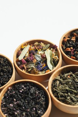Different types of green, black and herbal tea in a wooden bowl. Variety of dry leaves and flowers. Organic high-quality ingredients for a drink