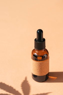 Bej arka planda tıbbi amaçlar için kullanılan kenevir yağlı Amber cam damlası şişeleri. Gün ışığı ve kenevir yaprağının gölgesi. Sakinleştirici cbd yağı. Alternatif tıp. Boşluğu kopyala
