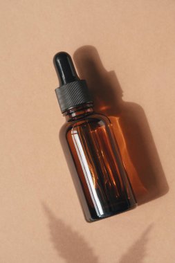 Bej arka planda tıbbi amaçlar için kullanılan kenevir yağlı Amber cam damlası şişeleri. Gün ışığı ve kenevir yaprağının gölgesi. Sakinleştirici cbd yağı. Alternatif tıp. Boşluğu kopyala