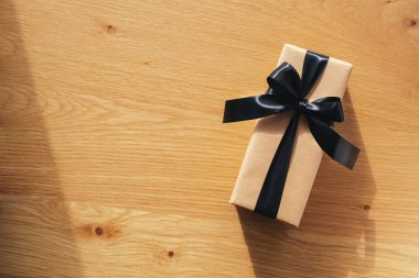 Kraft hediye kutusu, üzerinde siyah iplik olan tahta bir arka plan. Kutlama için hediye paketleme ve hazırlama. Noel, Yeni Yıl veya doğum günü arkaplanı.