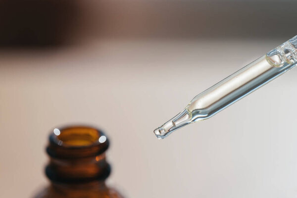 Открытая янтарная бутылка с пипеткой капельницы с сывороткой или эфирным маслом. Продукты по уходу за кожей, натуральная косметика на размытом фоне. Медицина и концепция красоты для ухода за лицом. Селективный фокус в центре