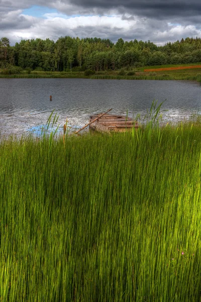 Wooden boat in a lake behind reed — Stock Photo, Image