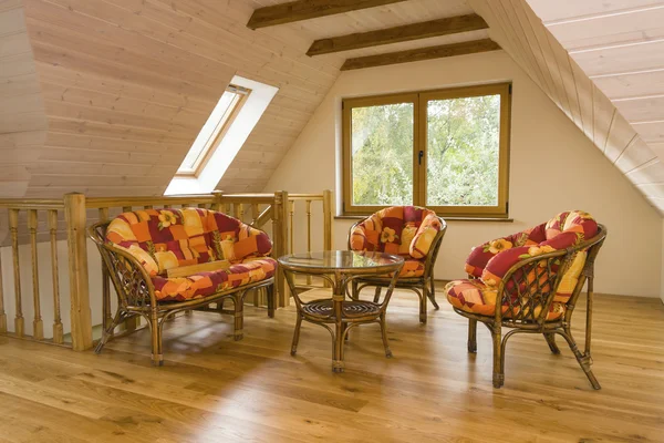 Мансардна кімната з садовими меблями. Стіни покриті дерев'яним планом Стокове Фото