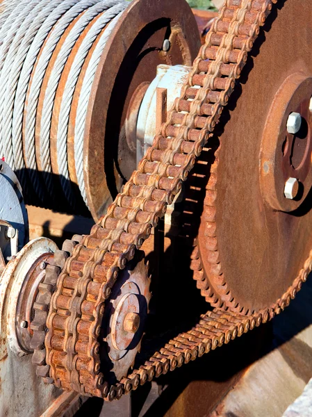 La transmisión de cadena oxidada consiste en una rueda dentada grande y una pequeña y una cadena fuerte grande —  Fotos de Stock