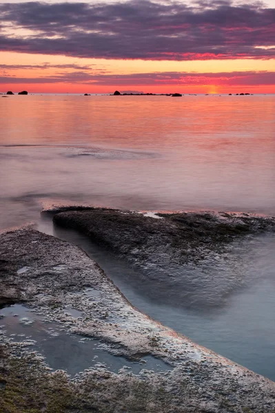 Beautiful sunset at sea, large rocks in foreground — Stock Photo, Image