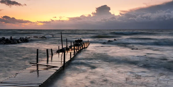Trä bro i havet vid solnedgången — Stockfoto