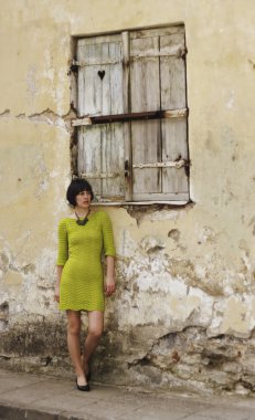 yeşil elbiseli kadın eski duvara eğilir