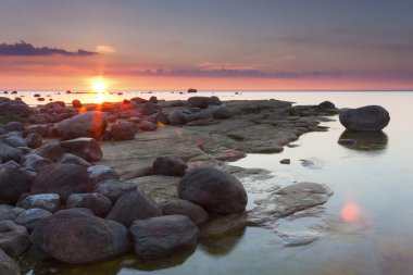 günbatımı kayalık sahil arkasında