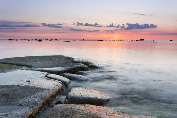 Günbatımı kayalık sahil arkasında — Stok fotoğraf