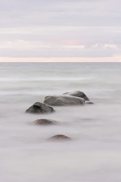 Steine im Ozean bei Sonnenuntergang — Stockfoto