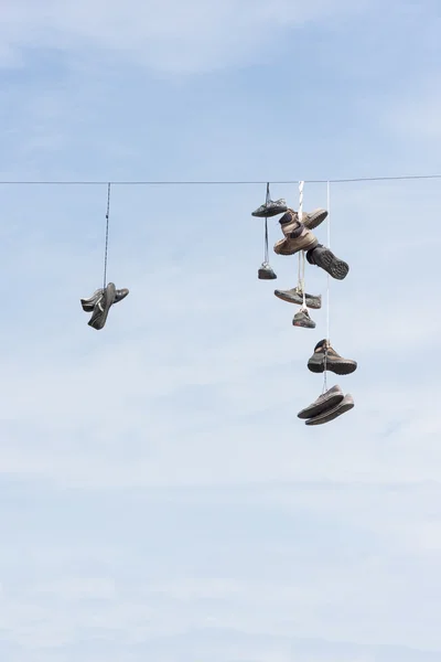 Gamla slitna stövlar eller skor hänga på en kabel — Stockfoto