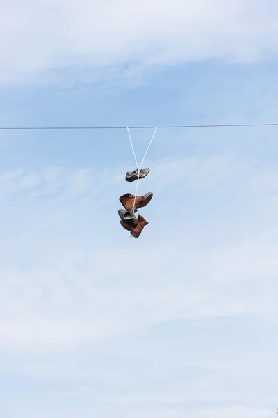 Old worn boots or shoes hang on a cable — Stock Photo, Image