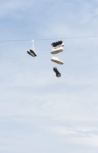 Botas viejas o zapatos desgastados cuelgan de un cable — Foto de Stock