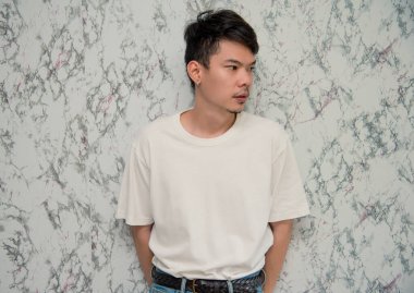 Beyaz arka planda yakışıklı genç bir adam. Fotoğraf stüdyosuna bakıyor. Asya