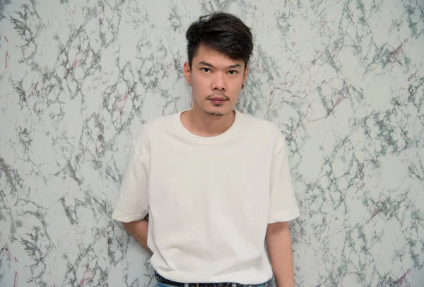 Beyaz arka planda yakışıklı genç bir adam. Fotoğraf stüdyosuna bakıyor. Asya