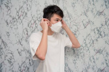 Genç adam, beyaz arka planda izole edilmiş karantina sırasında virüsten korumak için yüz maskesi takıyor.