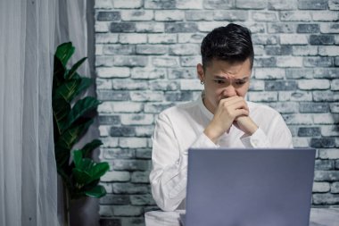 Evde dizüstü bilgisayarla çalışırken yakışıklı bir genç.