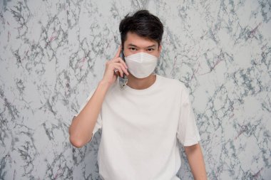 Adam beyaz arka planda izole edilmiş akıllı telefonu kullanarak yüz maskesi takıyor. Salgın ve sosyal uzaklık kavramı. Covid-19