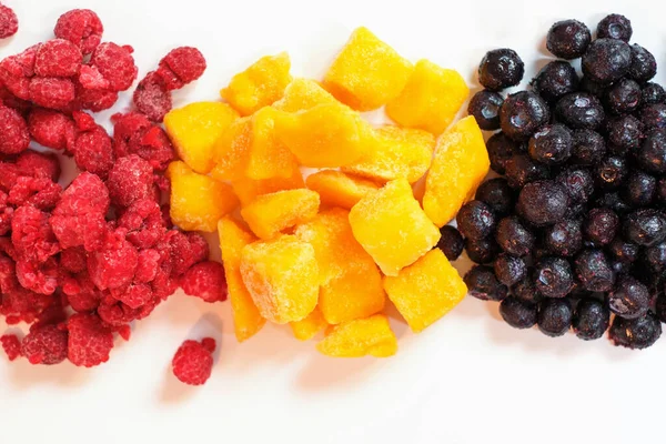 Frozen mango, blueberry and raspberry close-up, top view.