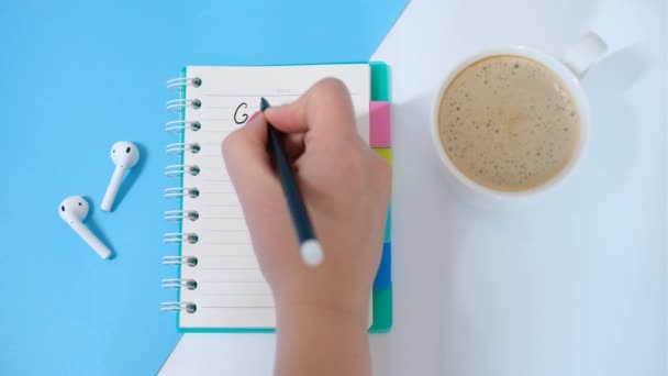 Ženská ruka píše cíle v notebooku na bílém a modrém pozadí. — Stock video