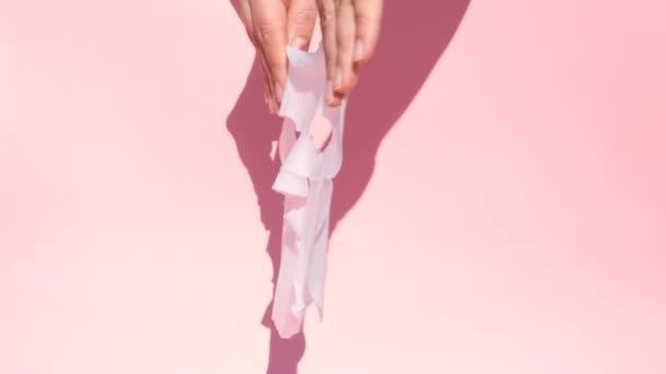 女性の手はピンクの背景に白いシートマスクを保持. — ストック動画