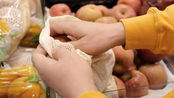Las manos masculinas apilan manzanas en una bolsa ecológica en el primer plano del supermercado. — Vídeos de Stock
